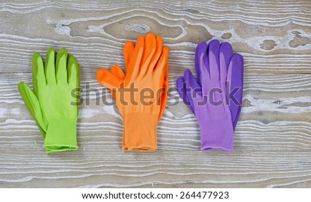 Brand new colorful garden gloves on top of rustic white wooden boards. Layout in horizontal format.