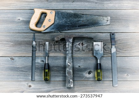 Vintage concept of used tools on rustic wooden boards consisting of hammer, metal files, hand saw, and chisels.