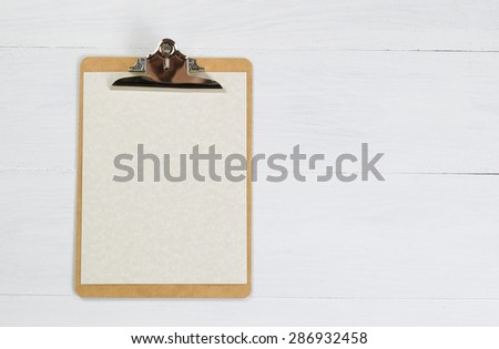 Blank clipboard with paper on white desktop.