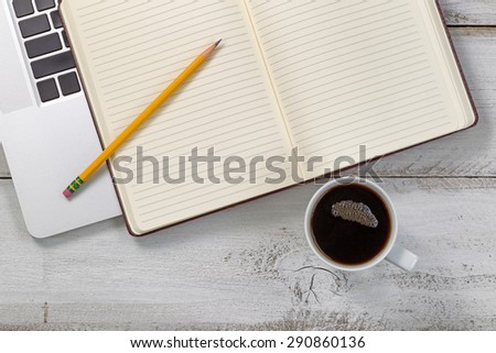 Old white wooden desk with laptop, notepad, pencil and dark coffee.