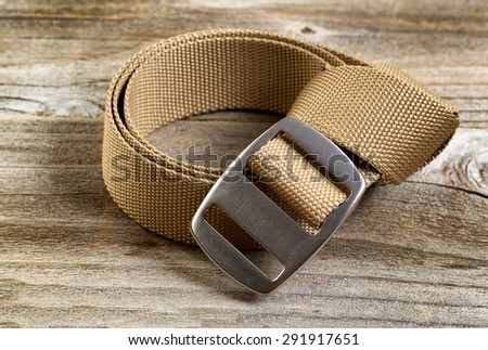 Close up view of a brand new utility belt with large buckle on rustic wooden boards.