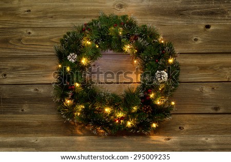 Christmas wreath with white lights on rustic wooden boards.  Low lighting to bring out glow of lights.