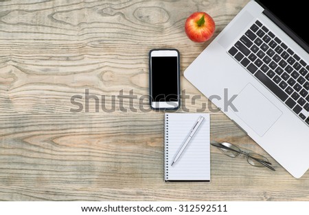 Top view of a organized, slightly fading, wooden desktop with apple for snack. Plenty of copy space.