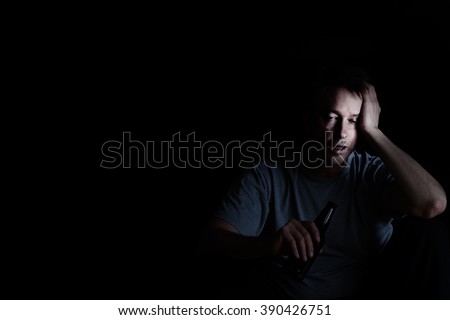 Depressed mature man drinking in dark. Selective focus on face with light. Depression concept.
