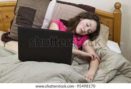 stock photo Young Preteen Asian girl falls asleep with laptop while in bed
