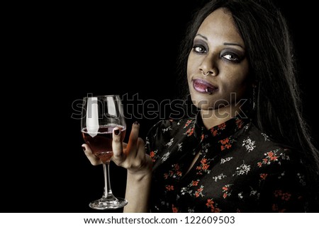 A sexy gothic african american holding a glass of wine against a dark background.