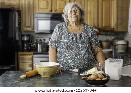 Grandmother or mother in the kitchen by baking supply with a big smile as she gets ready to bake.