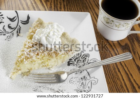 Slice of coconut cream pie with a cup of coffee
