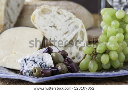 Close up of a tray of assorted rustic bread and cheese with olives and grapes