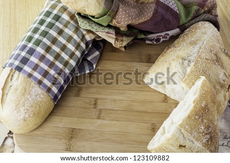 whole rustic bread wrapped in kitchen towels on cutting board with space for your personal text
