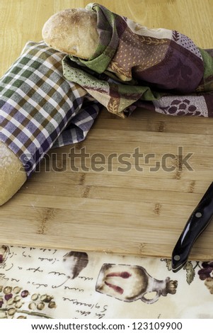 whole rustic bread wrapped in kitchen towels on cutting board with space for your personal text