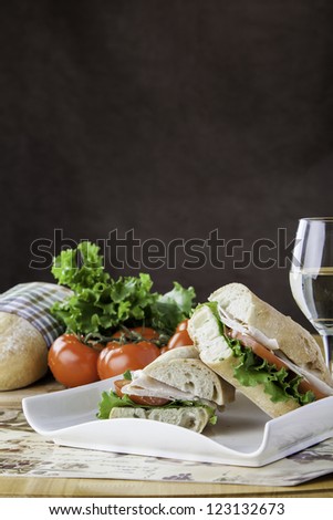 Turkey sub on rustic bread with tomato, bread, lettuce and cheese in the background with space for personal text