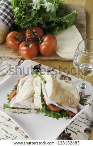 Turkey sub on rustic bread with tomato, bread, lettuce and cheese overhead view