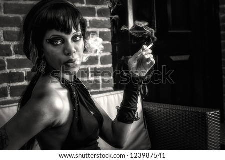 Sexy african american gothic woman smoking. Creative, dramatic lighting with smoke, sexy eyes, seductive look, black and white photo