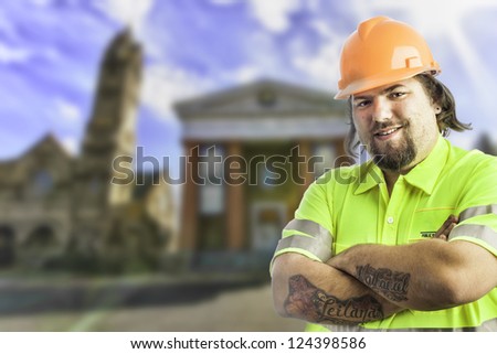 City construction worker arms crossed, tattooed with blurred city buildings behind him
