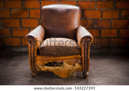 The grunge old armchair with top hi-light over the brick wall
