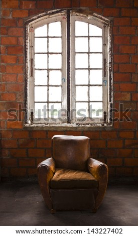 The grunge old armchair with top hi-light over the large window