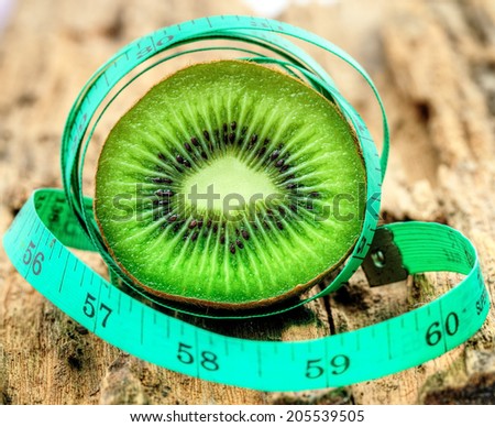 Kiwi fruit with meter tape on old wood