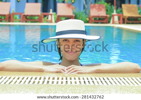 Young woman relaxing in swimming pool, tropical country.