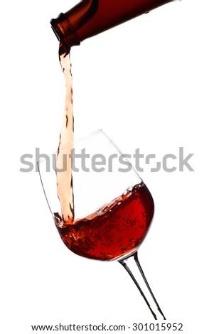 Red wine being in glass isolated on white background. Splashing stop motion.