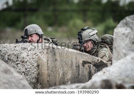 two united states soldiers defending, behind concrete block