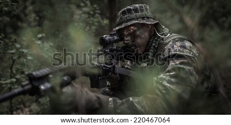 U.S. soldier dressed in tiger stripe camouflage, hidden in jungle