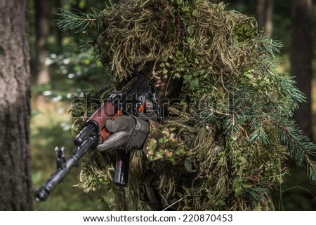 special forces soldier wearing heavy camouflage, moving silently through forest. Ghillie suit with natural plants.