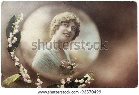 GERMANY - CIRCA 1908. Vintage postcard  printed by GERMANY shows hand painted photograph of beautiful young woman with lilies of the valley, circa 1908.
