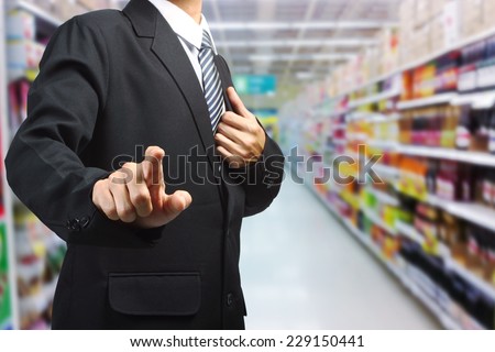 Business Man pushing on a touch screen interface in supermarket in blurry