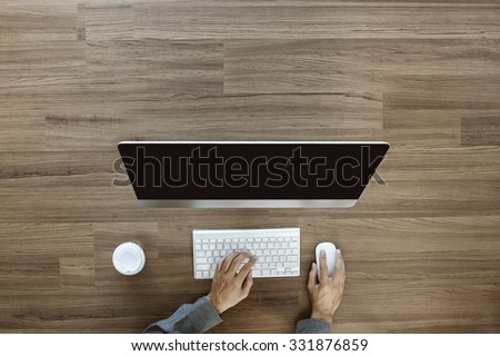 Businessman working at office desk and using a desktop computer on table, View from above with copy space for design work