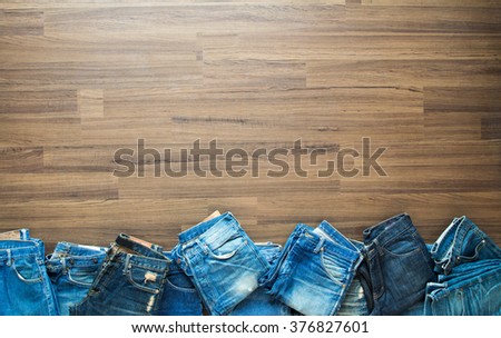 Jeans stacked on a wooden background, View from above with copy workspace