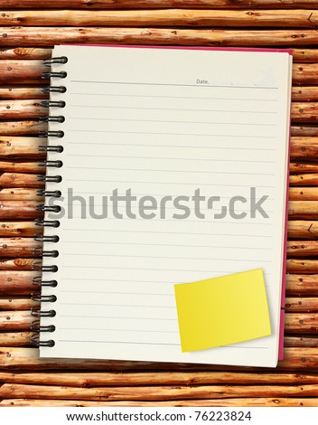 blank spiral book with yellow note paper. on wood background