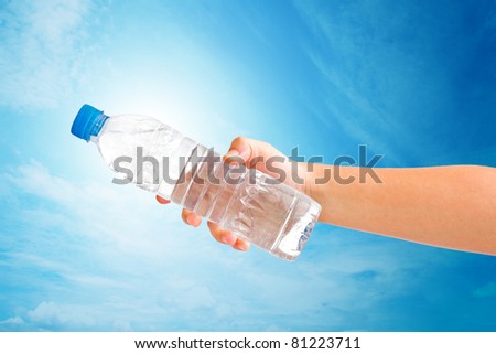 hand holding a bottle of water on blue sky. save path for isolated design work