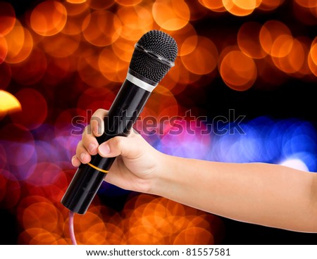 Microphone in a hand on bokeh abstract light background. save path for isolated design work