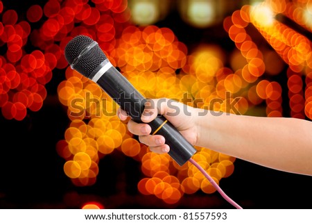 Microphone in a hand on bokeh abstract light background. save path for isolated design work
