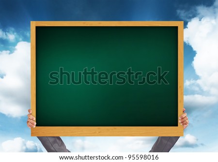hand holding blank chalkboard on blue sky background