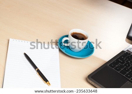 Office setup - pen and paper, coffee and laptop - focus on coffee