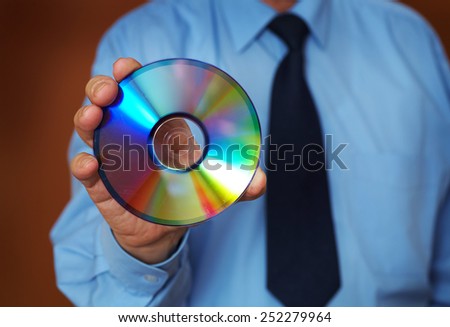 A man in a blue shirt and tie holds CD