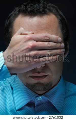 A Businessman covers his eyes his hands