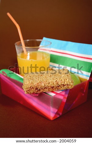 Healthy lunchbox containing orange juice, apple and an oat bar.