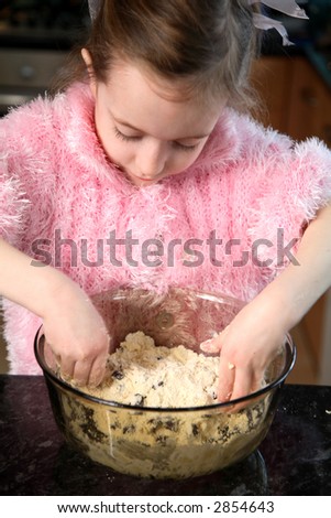 Young girl mixing food ingredients in a bowl with her hands