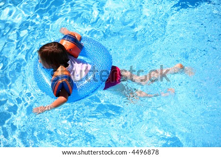 Young girl swimming with arm bands and a ring