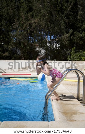 Girl about to jump into a swimming pool holding her nose