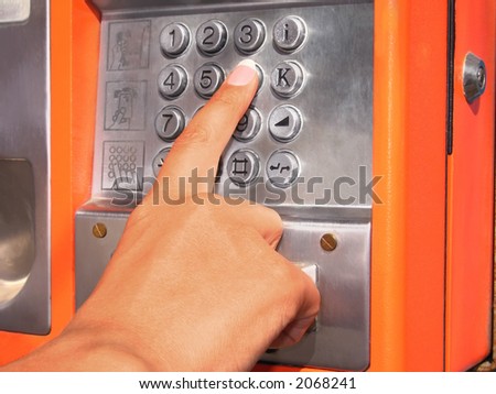 woman's hand dialing a public phone