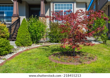 Nicely decorated front yard. Flowers and stones in front of the house. Landscape design.