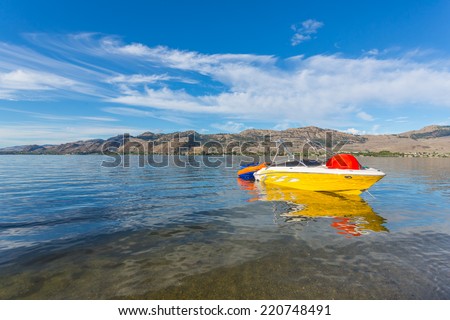 Boat and water tube on the Osoyoos lake in Canada with mountains and blue sky