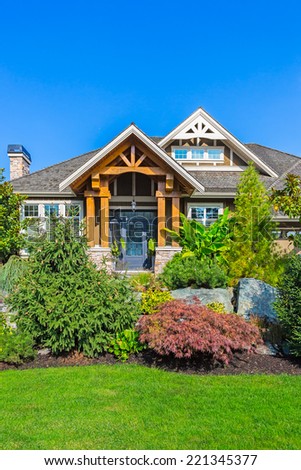 Custom built luxury house entrance with nicely trimmed and landscaped front yard in Canada.