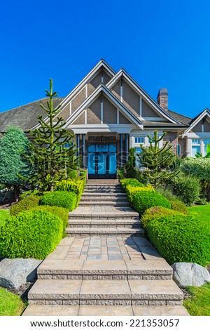 Custom built luxury house with nicely trimmed and designed front yard, lawn in a residential neighbourhood in Canada. Entrance to the house.