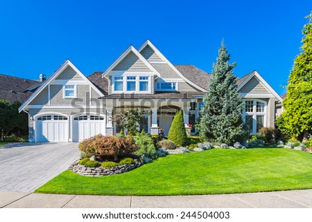Custom built luxury house with nicely trimmed and landscaped front yard lawn and driveway to garage in a residential neighborhood. Vancouver Canada.