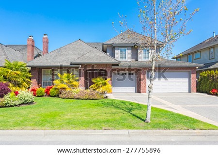 Custom built luxury house with nicely trimmed and designed front yard, lawn in a residential neighbourhood in Canada.